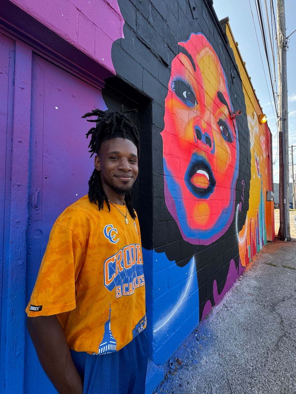 Zay Williams in front of newly painted mural at Celebrity's Beauty Supply