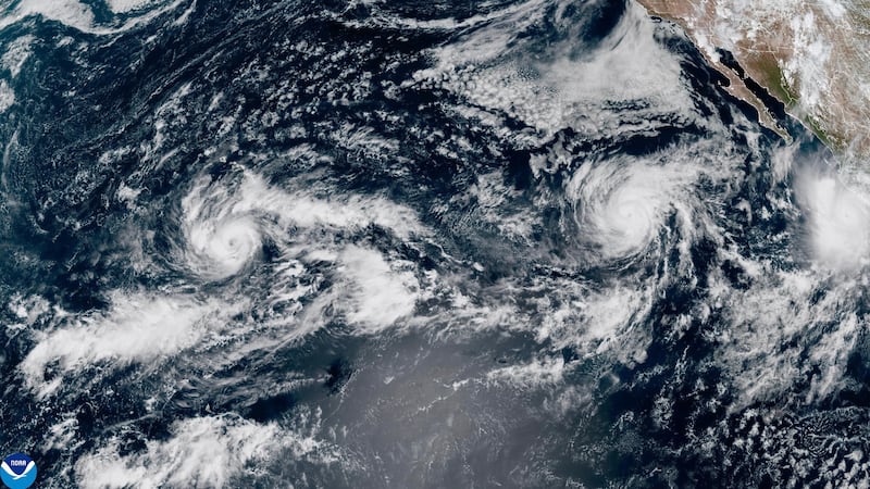 This satellite image provided by NOAA shows Tropical Storm Nolo, left, south of Hawaii;...